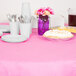 A table with a Creative Converting Candy Pink table cover, plates, and utensils on it.