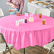 A table with a pink Creative Converting tablecloth and glasses of liquid.