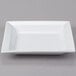 A white square porcelain bowl on a white square plate.