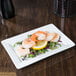 A Libbey rectangular white porcelain plate with shrimp and lemon slices on it.