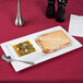 A Libbey white porcelain soup and sandwich tray with a grilled sandwich and a spoon on it.