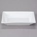 A white rectangular dish with a wide rim and a square bowl on a white surface.