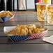 A #500 USA flag paper food tray filled with patriotic potato chips and cheese sauce on a table.