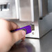A hand plugging a purple USB drive into a device.