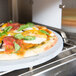 A Bakers Pride E300 high-speed countertop oven cooking a pizza with tomatoes, jalapenos, and vegetables.
