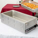 A stainless steel countertop warmer with trays of food on it.