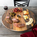 An American Metalcraft faux acacia melamine serving board with cheese, salami, and grapes on a table.