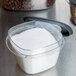 A Rubbermaid clear plastic container with white powder inside on a kitchen counter.