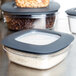 A Rubbermaid clear square food storage container with rice in it.