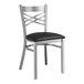 A Lancaster Table & Seating metal cross back chair with a black cushion.