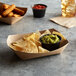 A Natural Eco-Kraft paper food tray with bowls of chips and dips on it.
