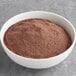 A bowl of Ghirardelli Sweet Ground Chocolate & Cocoa Powder on a gray surface.