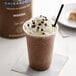 A close-up of a Ghirardelli Mocha Frappe Mix in front of a cup of coffee.