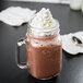 A glass mug filled with Ghirardelli Frozen Hot Chocolate Frappe Mix and whipped cream.