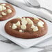 A chocolate chip cookie with Regal Classic White Chocolate chips on a plate.