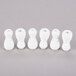 A group of white plastic plugs on a grey surface.