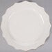 A white stoneware plate with a brown rim and scalloped edges.