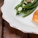 A 10 Strawberry Street Oxford brown rim stoneware plate with a piece of salmon and green beans on a wood table.