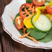 A 10 Strawberry Street brown stoneware salad plate with a variety of vegetables including orange carrots.