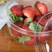 A Dart clear plastic bowl filled with strawberries.