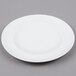 An Arcoroc white porcelain bread and butter plate with a white rim on a gray surface.