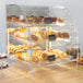A Vollrath bakery display case filled with bagels, pastries, and cupcakes.