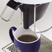 A Curtis white coffee maker pouring a cup of coffee.