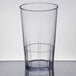 A Cambro clear plastic tumbler with a clear liquid inside on a table.