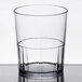 A clear Cambro plastic tumbler with a black rim filled halfway with liquid.