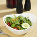 A white porcelain bowl filled with salad and vegetables with a fork.