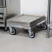 A Channel bun pan dolly with a stack of metal trays on wheels.