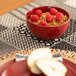 A red Wazee Matte stoneware cereal bowl with raspberries on a table.