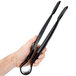 A hand holding a pair of black Thunder Group polycarbonate flat grip tongs.