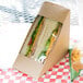 A sandwich in a Kraft paper sandwich wedge container with a window.