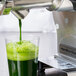 A Hamilton Beach wheatgrass juicer making green juice in a glass.