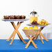 Tablecraft RFTT3BAM 3-Piece Fold-A-Way Bamboo Riser Set holding trays of food on a table.