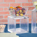 An American Metalcraft clear acrylic square riser with a bowl of fruit on it.