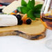 An American Metalcraft faux rustic wood melamine serving board with fruit and a glass of wine on a table.