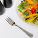 A plate of salad with vegetables and a Libbey Fairfield stainless steel salad fork.