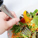 A hand holding a Libbey stainless steel salad fork over a vegetable salad.
