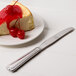 A piece of cheesecake with cherries on top and a Libbey Fairfield stainless steel utility knife.