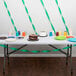 A table with an emerald green streamer and a chocolate cake on it.