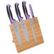 A Mercer Culinary Millennia Colors® 5-piece bamboo knife set with purple handles on a wooden stand.