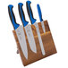 A Mercer Culinary Millennia Colors knife set with blue handles on an Acacia magnetic board.