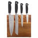 Three Mercer Culinary knives on a Genesis acacia magnetic cutting board.