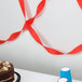 A Classic Red Streamer paper on a table with a cake and cups.