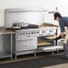 A man using a Cooking Performance Group commercial range with ovens to cook food.