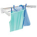 A white retractable wall mount drying rack with two blue shirts hanging from it.