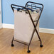 An antique bronze rectangular laundry hamper with a bag of clothes on wheels.