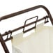 An antique bronze rectangular laundry hamper with a white bag on a metal bar.